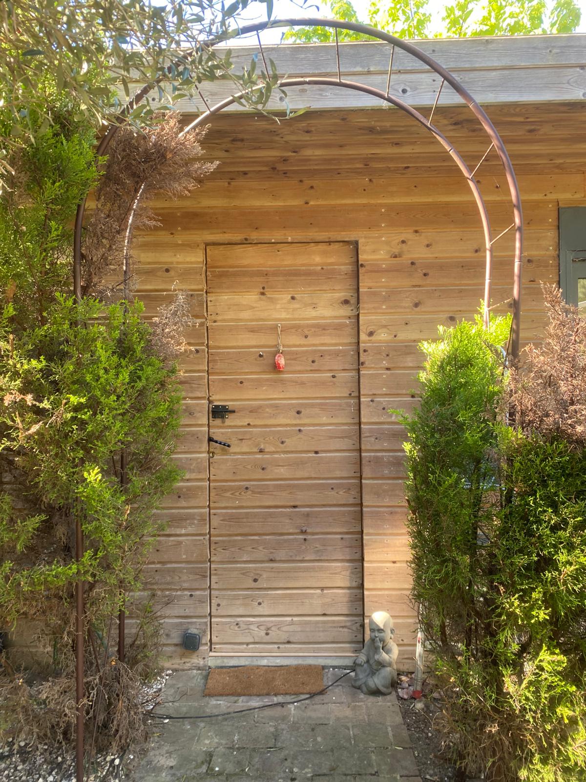 Entrée du cabinet Sangaia Kinésiologie - arche végétale et porte en bois